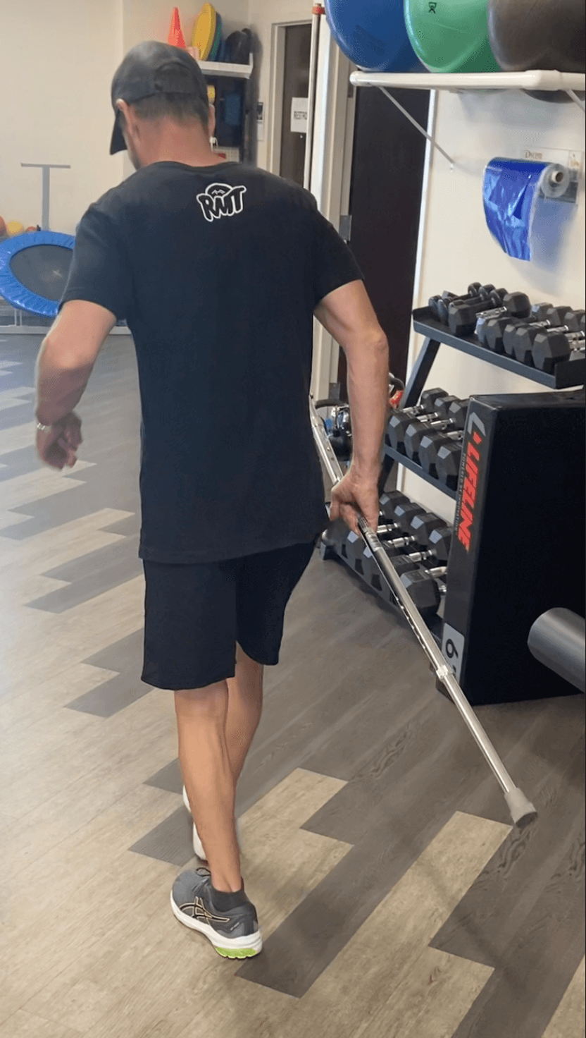 Michael Cavett walking with a cane in a physical therapy gym